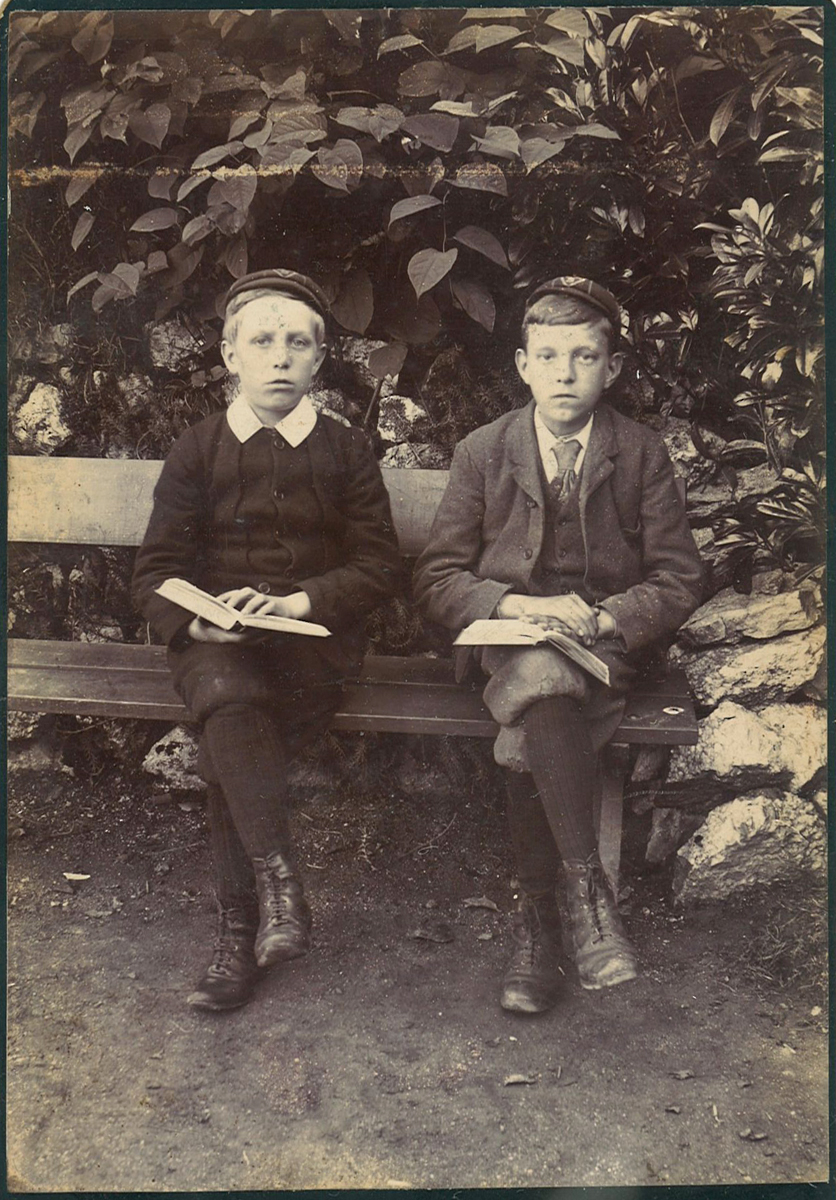 Two boys sat on bench reading