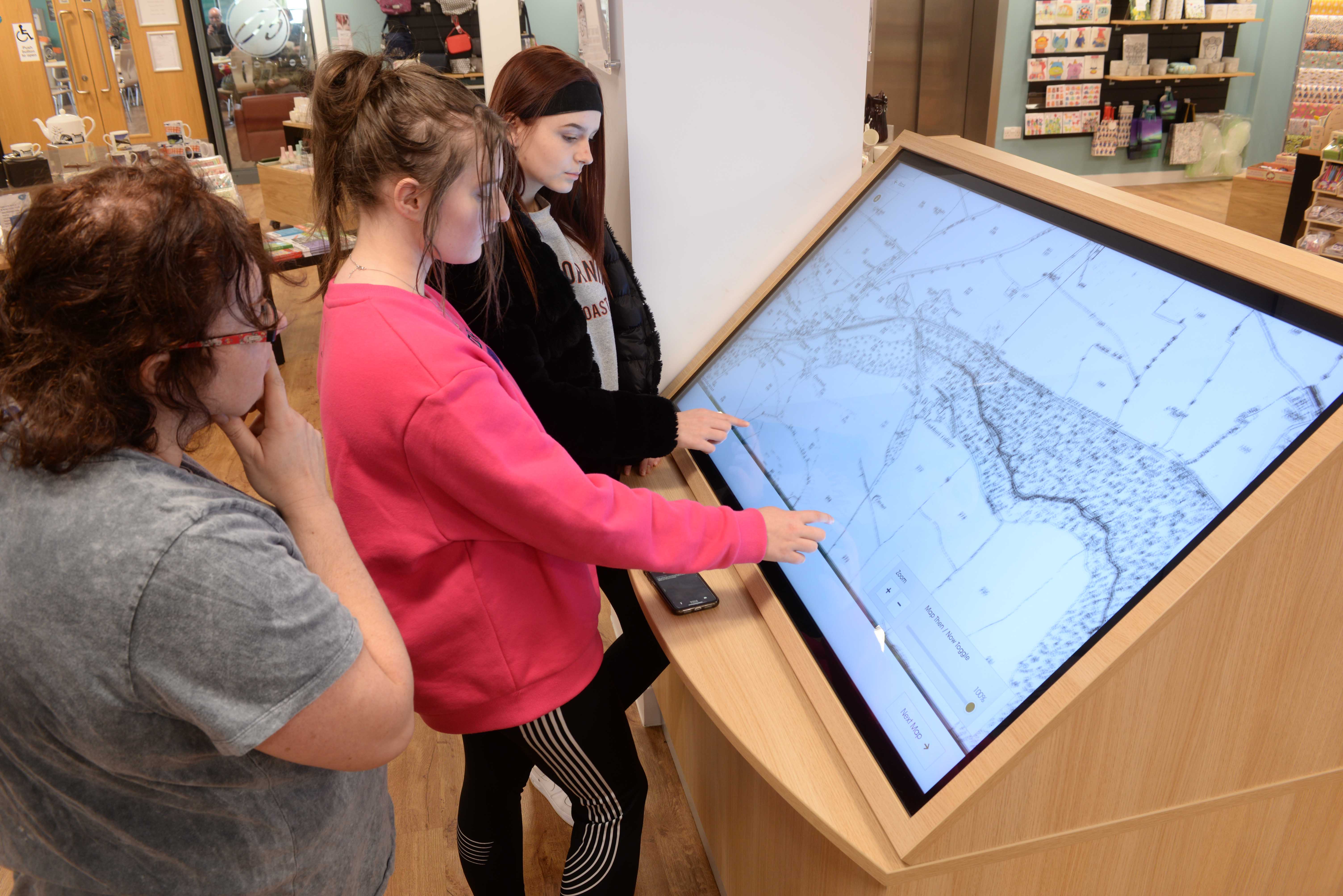 Teenagers using touch screen to showcase digital maps